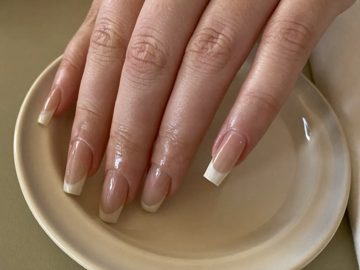Verzorgde nagels boven een keramisch schaaltje